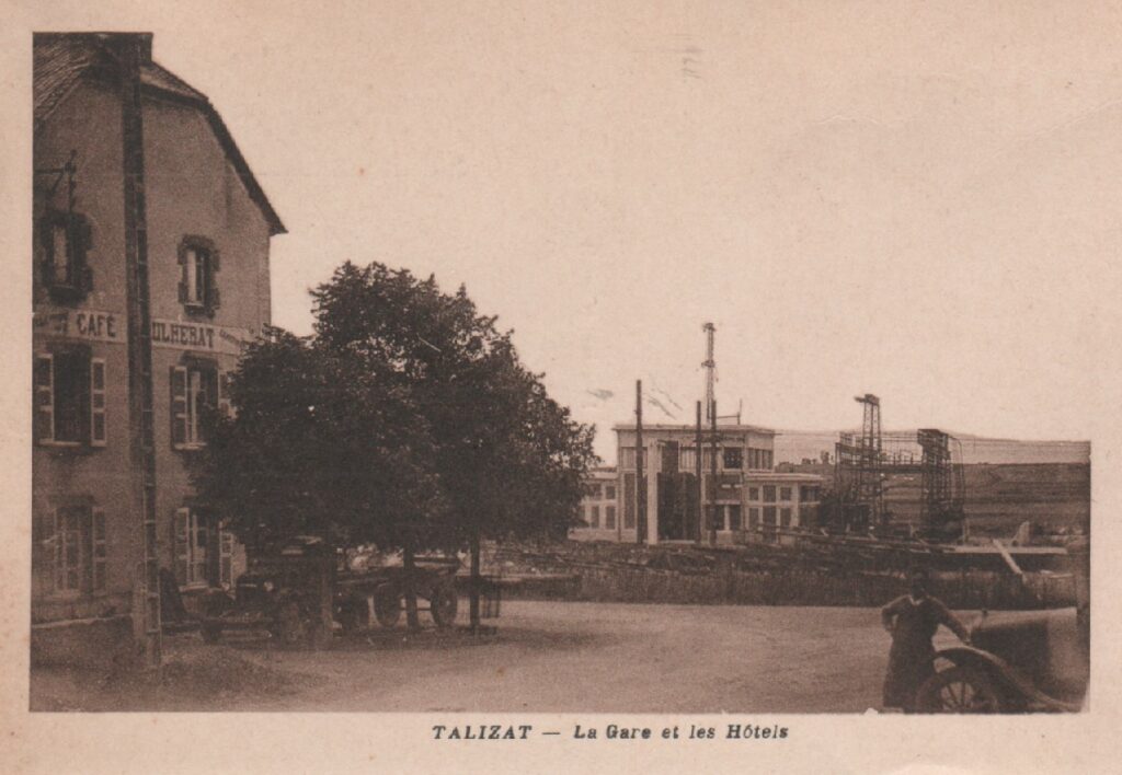 Carte postale ancienne de Talizat montrant la gare et un café-hôtel au premier plan